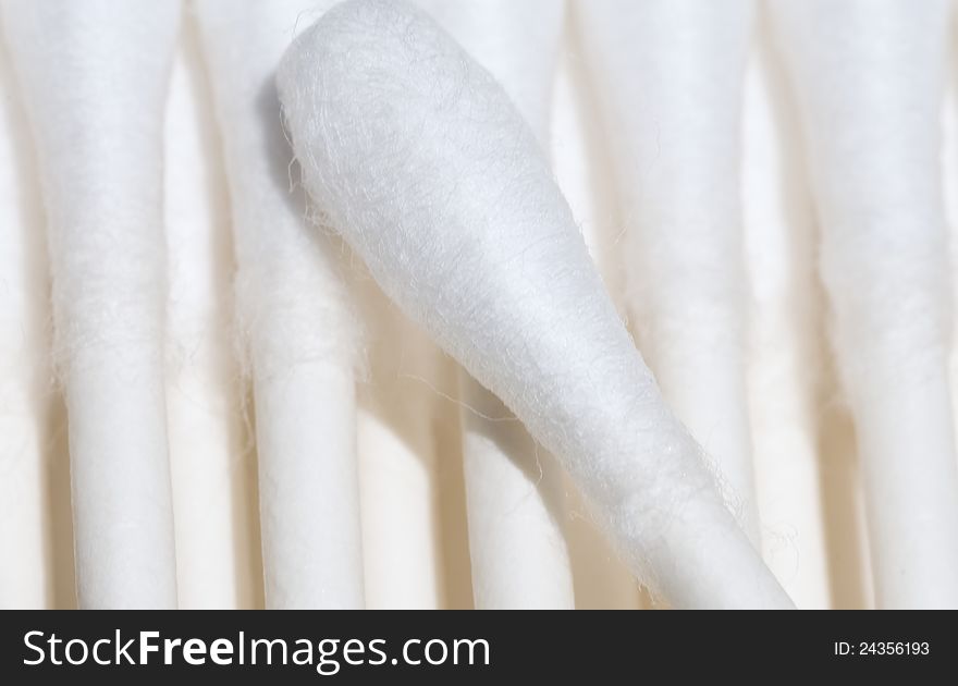 A photograph of a single cotton swab on a background of multiple cotton swabs