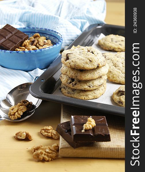 Fresh chocolate chip cookies on tray with chocolate and walnuts decoration