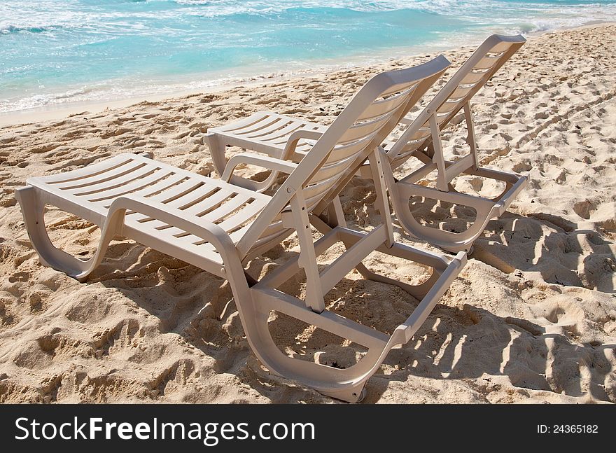 Two Sunbathing Chairs On The Beach