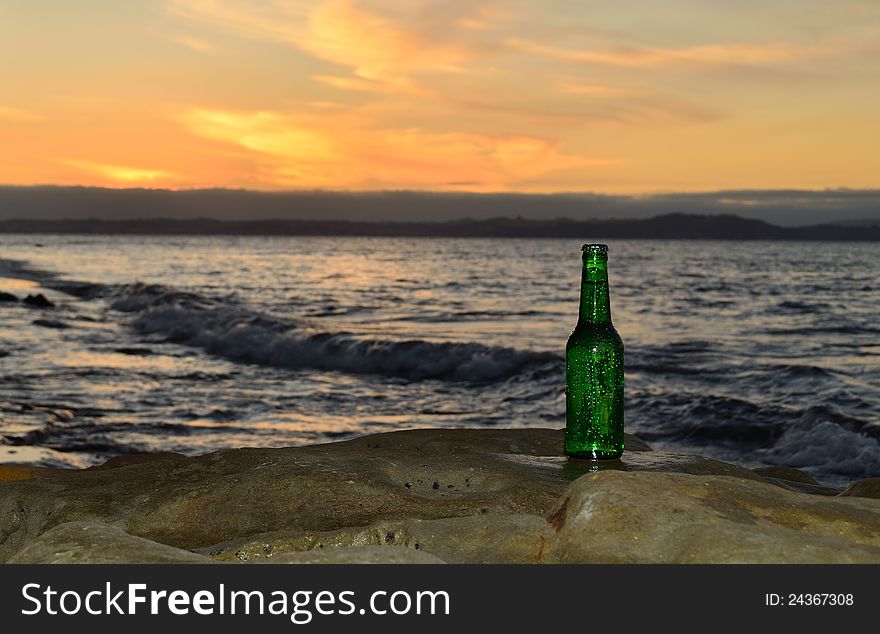 A wet beer bottle on the rocks at sunset. A wet beer bottle on the rocks at sunset.