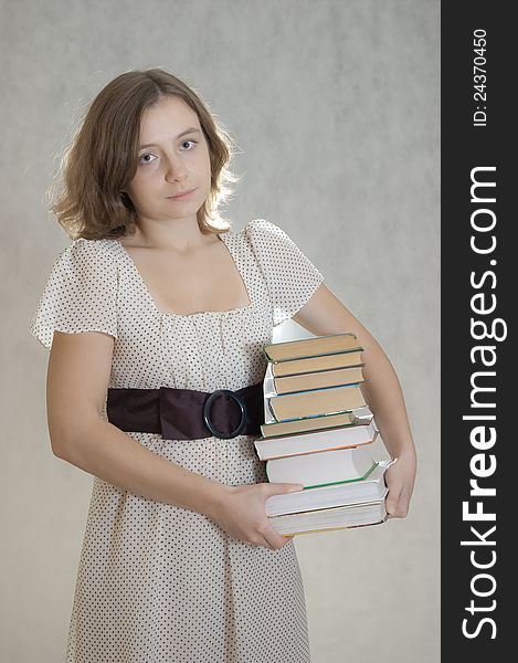 Sad girl carrying lots books under arm. Sad girl carrying lots books under arm