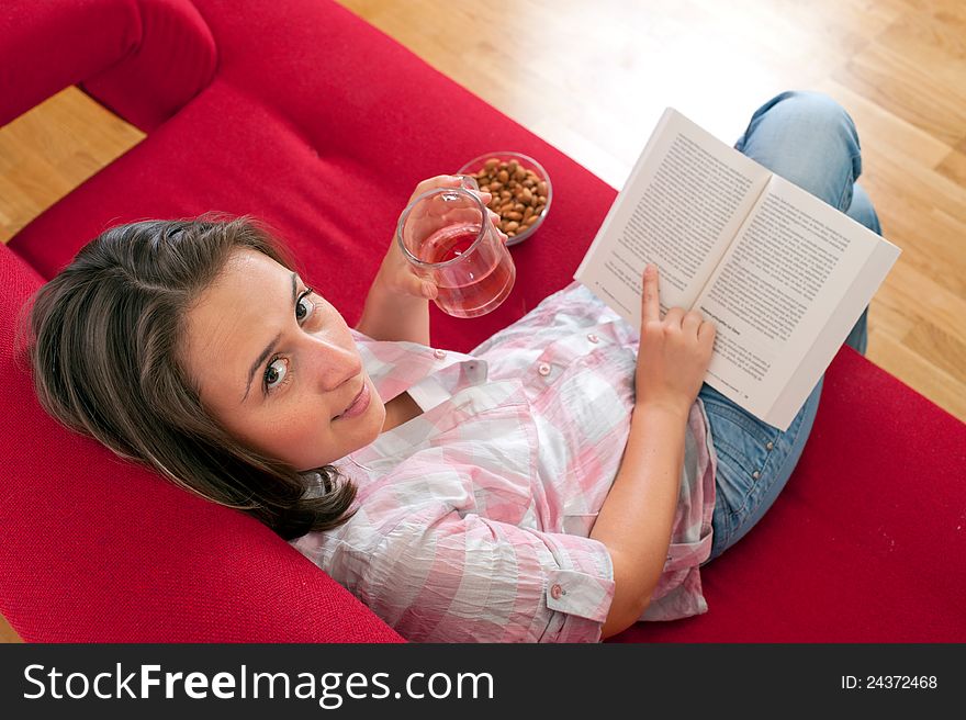Young woman relaxing and reading a book on a sofa