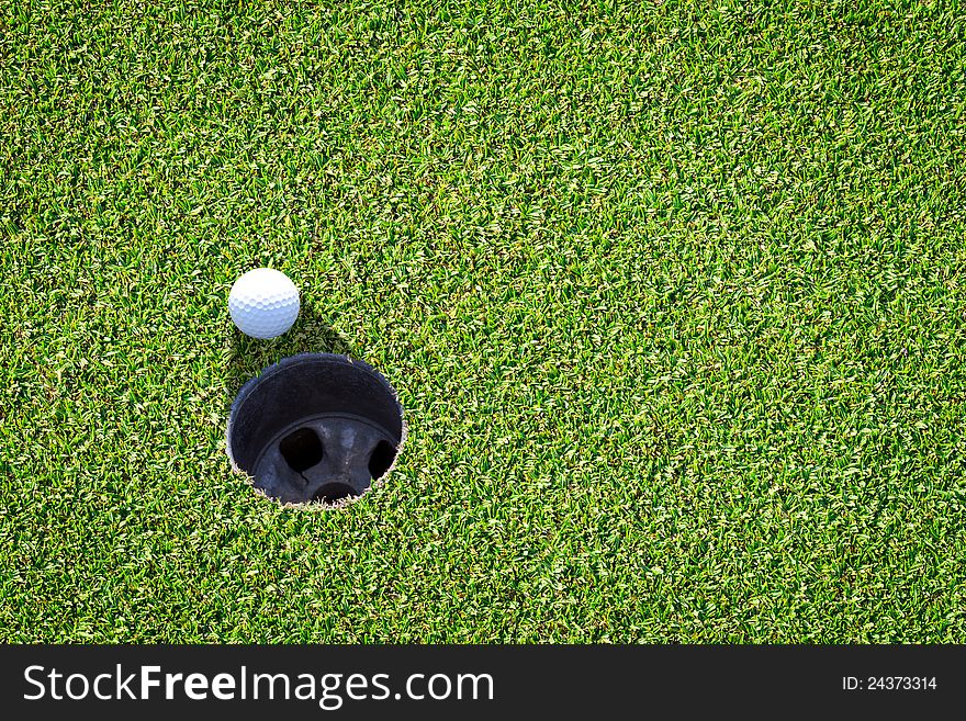 Golf ball very close to the hole. Golf ball very close to the hole