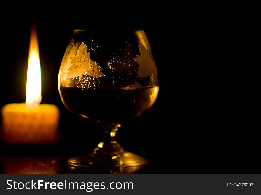 Glass of wine and burning candle on black background. Glass of wine and burning candle on black background