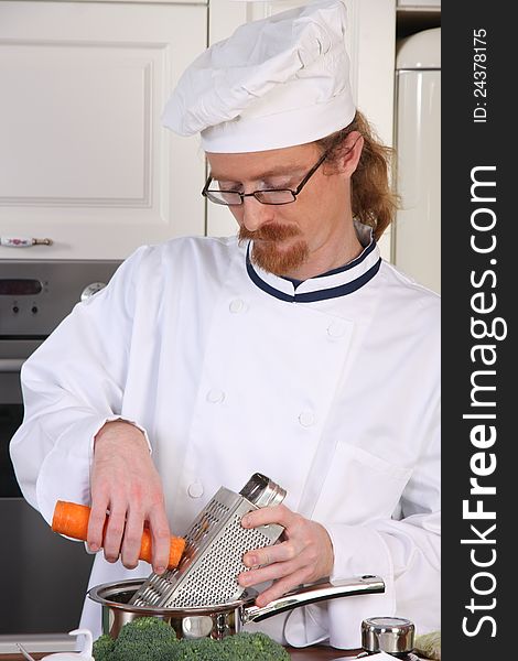 Young chef with carrot, preparing lunch in kitchen. Young chef with carrot, preparing lunch in kitchen