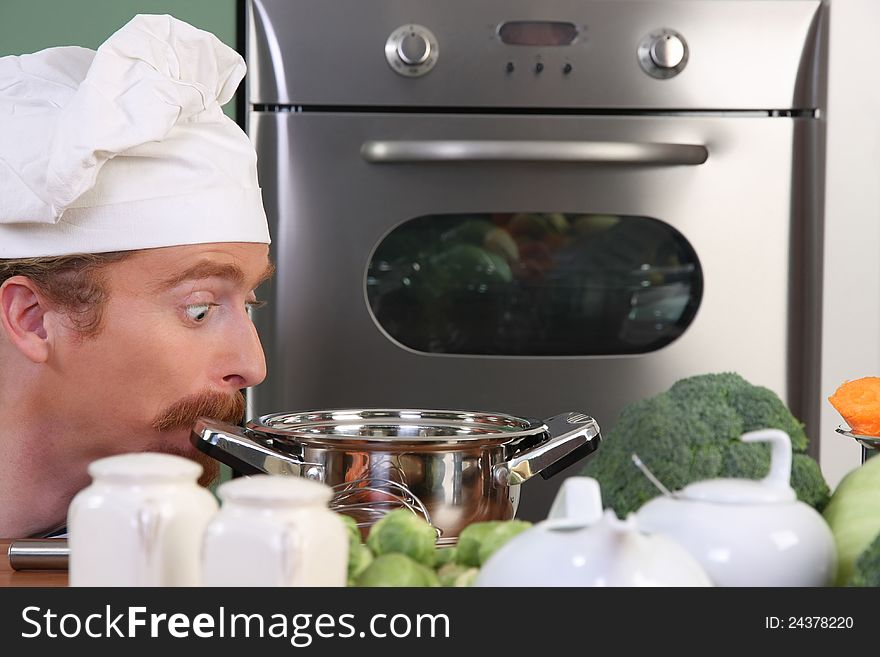 Funny young chef strange looking at pot