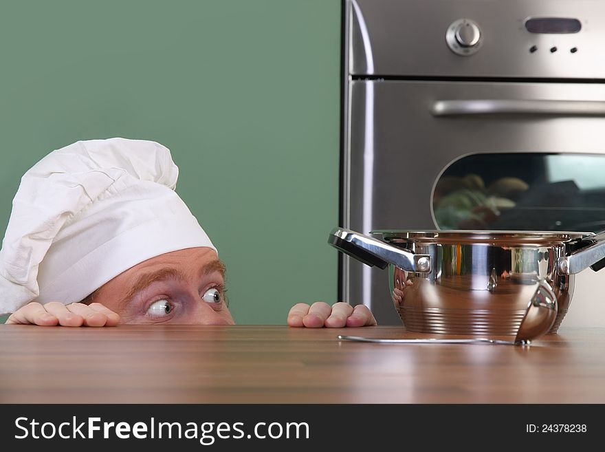 Funny young chef strange looking at pot