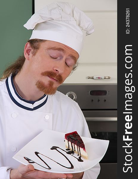 Funny young chef smelling a piece of cake with chocolate sauce