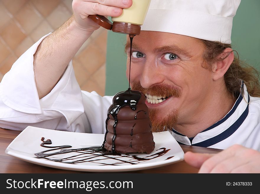 Funny young chef added chocolate sauce at piece of cake