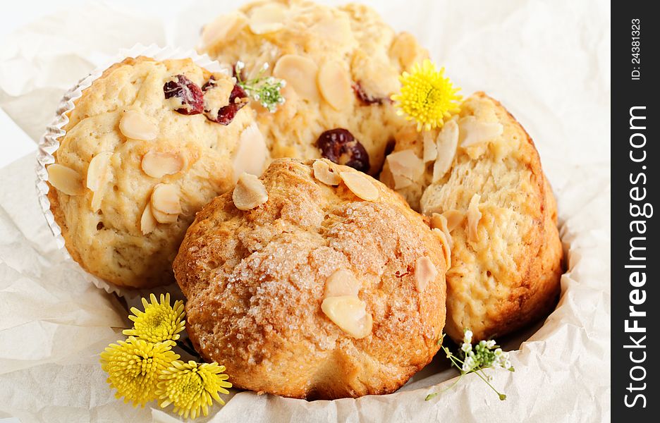 Almond muffins on paper basket and yellow flowers