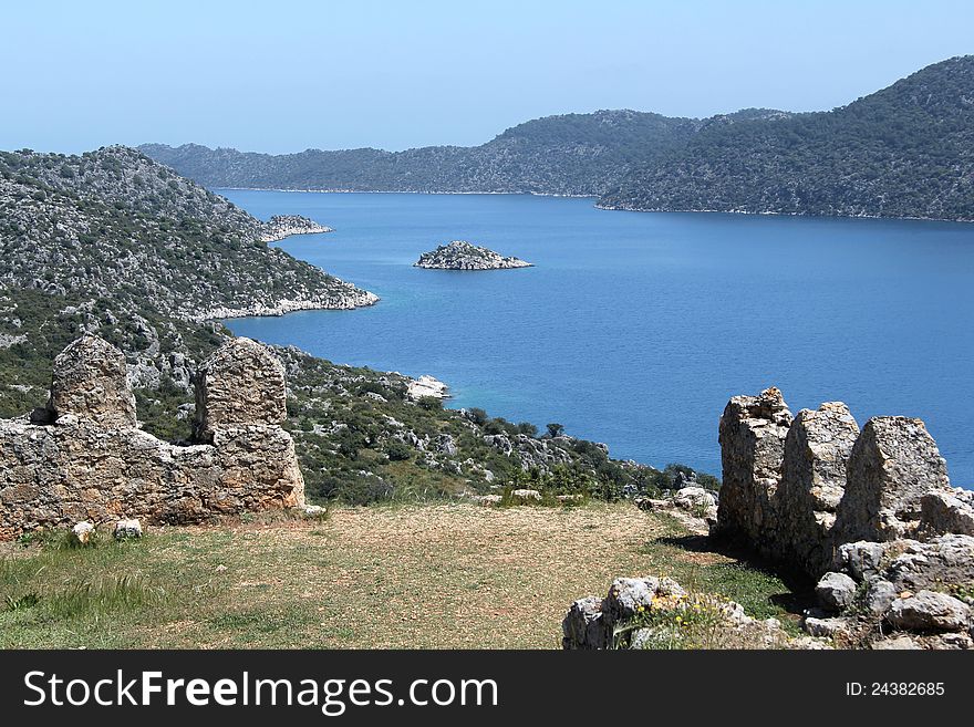 A break in the castle walls in Simena runs towards the sea in Turkey, shows the islands around the area. A break in the castle walls in Simena runs towards the sea in Turkey, shows the islands around the area.