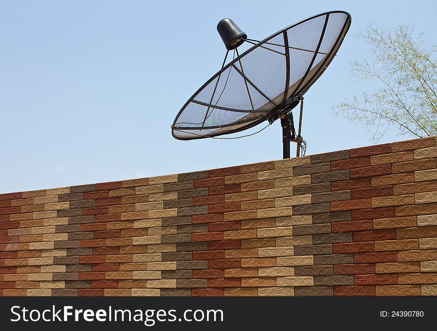 Black satellite dish above the modern brick walls. Black satellite dish above the modern brick walls.
