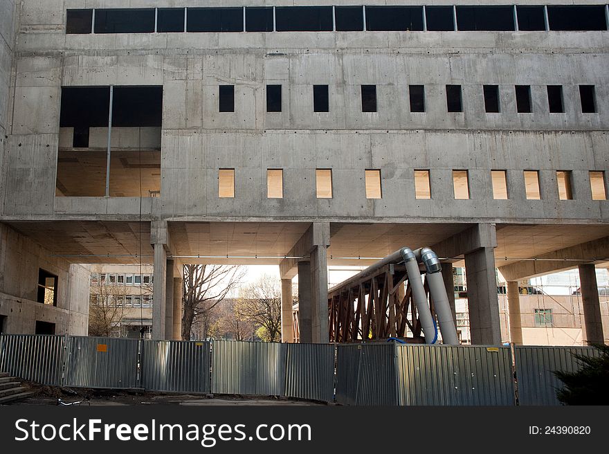 Building under construction. Concrete slab wall, fance in front and pipes. Horizontal photo. Building under construction. Concrete slab wall, fance in front and pipes. Horizontal photo.