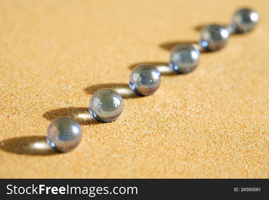 Abstract composition with few blue glass balls in a row on sand surface. Abstract composition with few blue glass balls in a row on sand surface