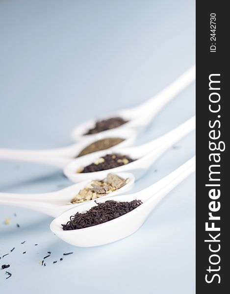 Four spoons with tea on blue background