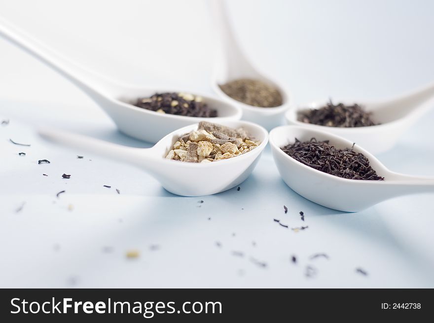 Four spoons with tea on blue background