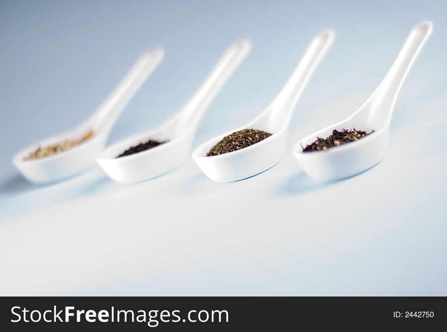 Four spoons with tea on blue background