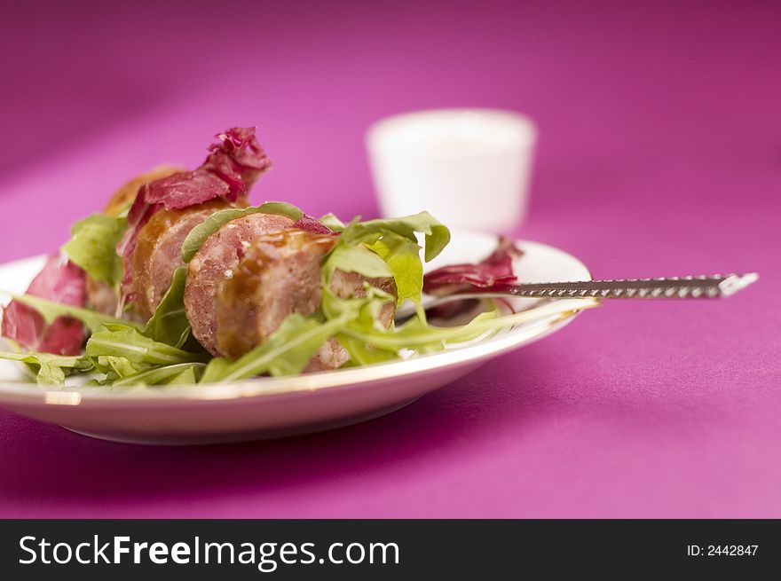 Sausage with salad on the pink background