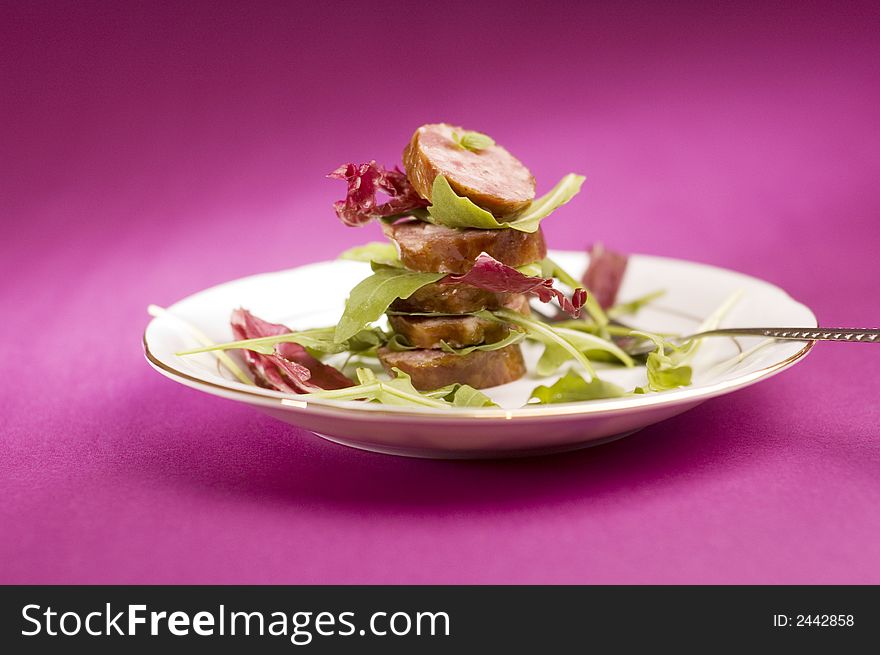 Sausage with salad on the pink background