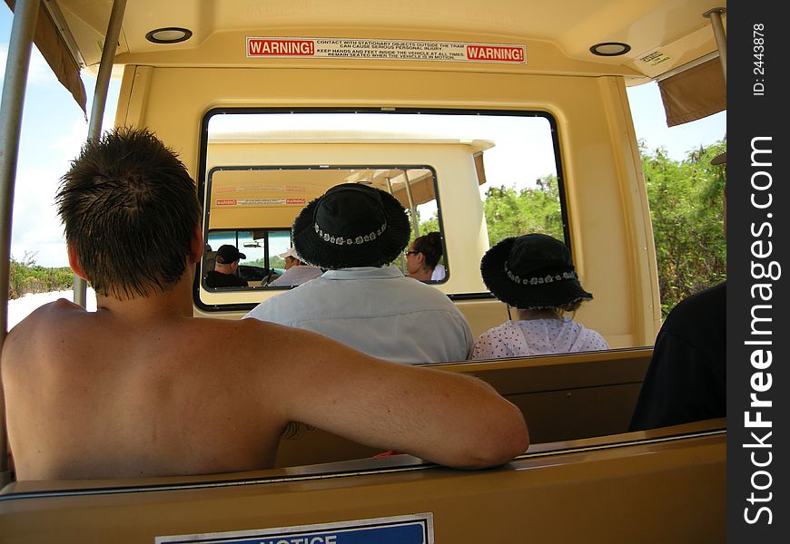 Picture taken on a tram ride showing the backs of the riders with various vacation attire. Picture taken on a tram ride showing the backs of the riders with various vacation attire.