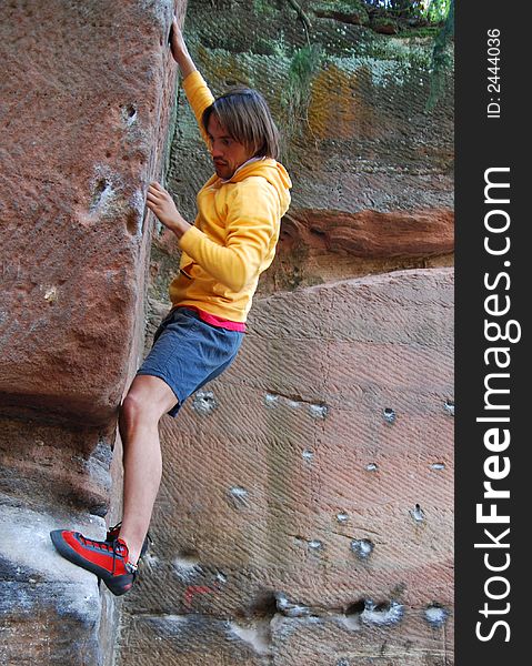 Young man is bouldering along a sandstone - wall without the secure-rope. Young man is bouldering along a sandstone - wall without the secure-rope