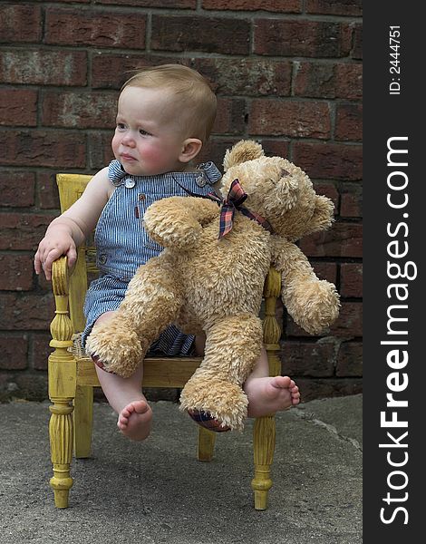 Image of cute toddler and teddy bear sitting in a chair