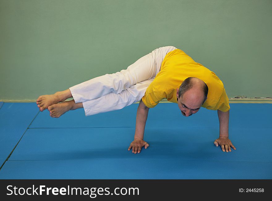 The man-yogi carries out Parshva Bakasana on blue floor