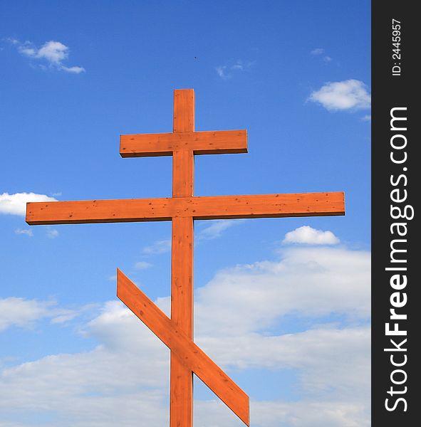 Wooden cross on a background of the blue sky with clouds