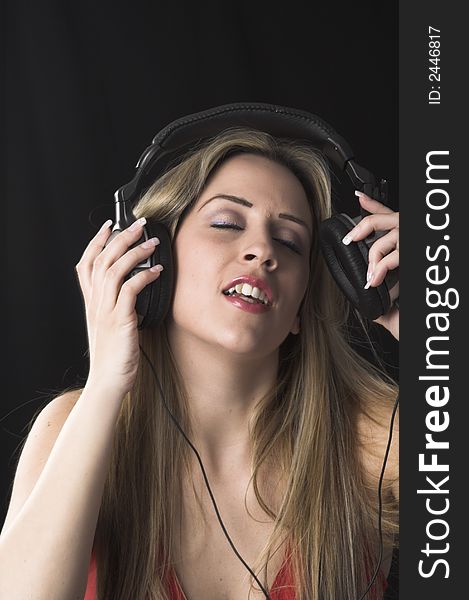 Fashion portrait of young woman listening to music over black background