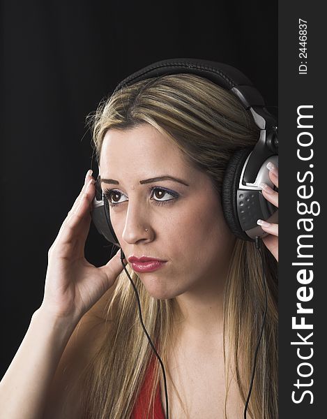 Fashion portrait of young woman  listening to music over black background