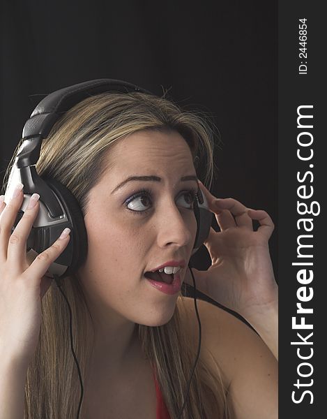 Fashion portrait of young woman listening to music over black background. Fashion portrait of young woman listening to music over black background