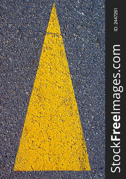 A yellow arrow symbol painted on a road. A yellow arrow symbol painted on a road