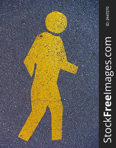 A yellow pedestrian symbol on a road. A yellow pedestrian symbol on a road