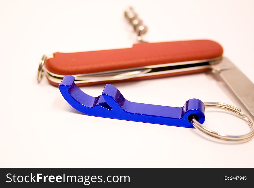 Bottle opener and pen-knife over white background