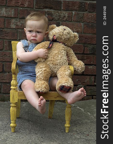 Image of cute toddler and teddy bear sitting in a chair