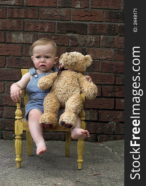 Image of cute toddler and teddy bear sitting in a chair