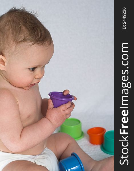 Image of an adorable baby playing with colorful stacking cups. Image of an adorable baby playing with colorful stacking cups