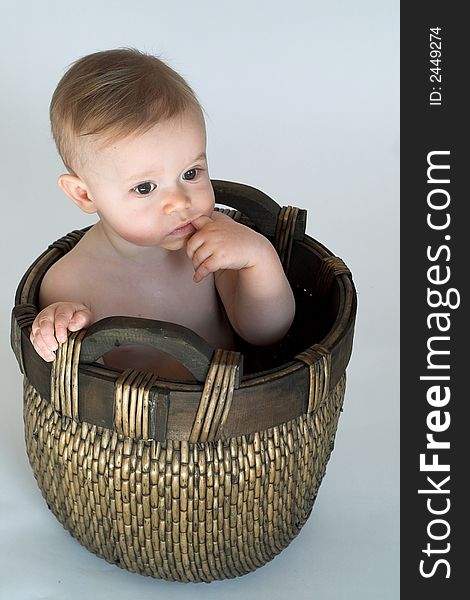 Image of cute baby sitting in a woven basket. Image of cute baby sitting in a woven basket