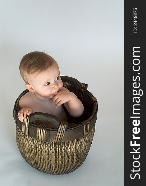 Image of cute baby sitting in a woven basket. Image of cute baby sitting in a woven basket