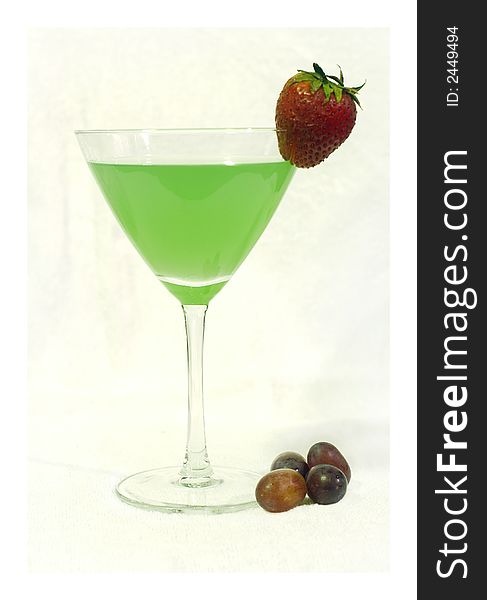 A summery green cocktail with some grapes and a strawberry on a white background. A summery green cocktail with some grapes and a strawberry on a white background.