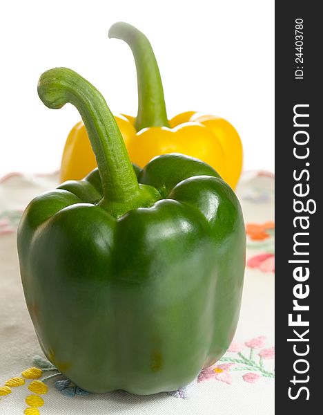 Green and yellow sweet peppers on embroidered tablecloth