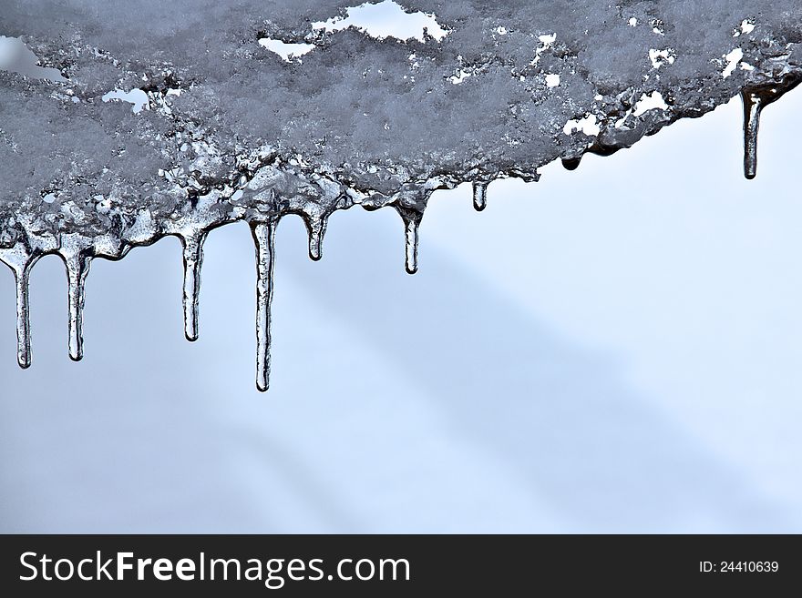 Closeup of icicles with blurred snow behind