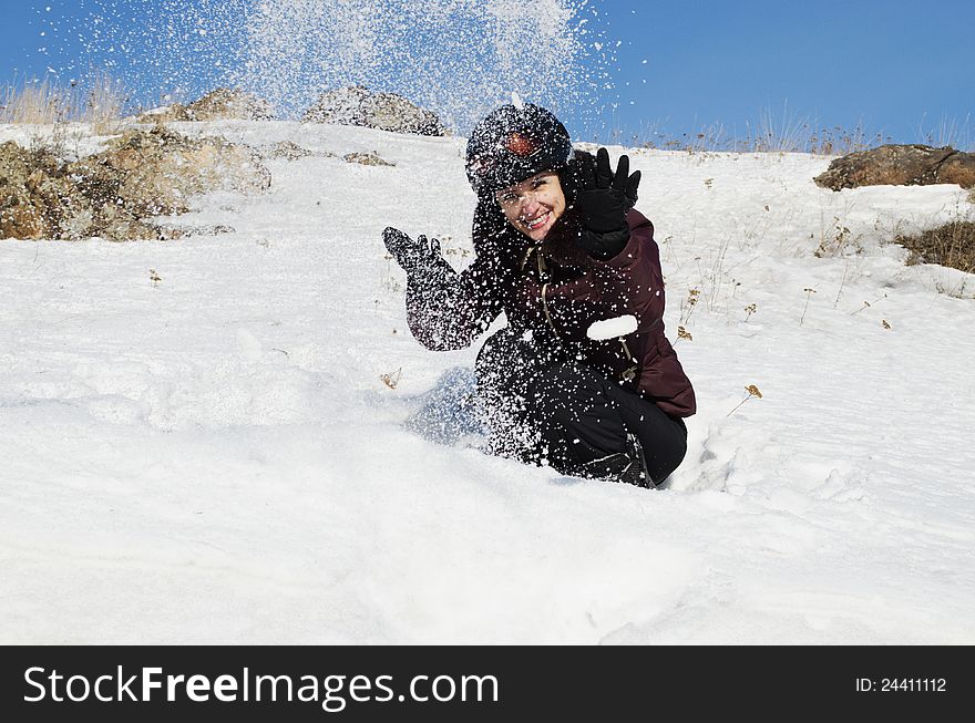 The beautiful young woman in mountain-skiing clothes has fun throwing upwards snow. The beautiful young woman in mountain-skiing clothes has fun throwing upwards snow