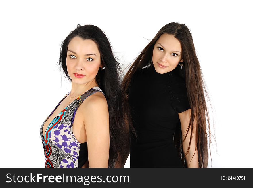 Two beautiful brunette girls look at camera inside white studio