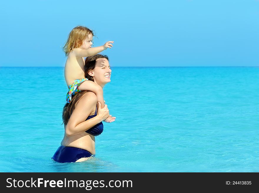 Happy child with her mother on the beach, summer vacation concept