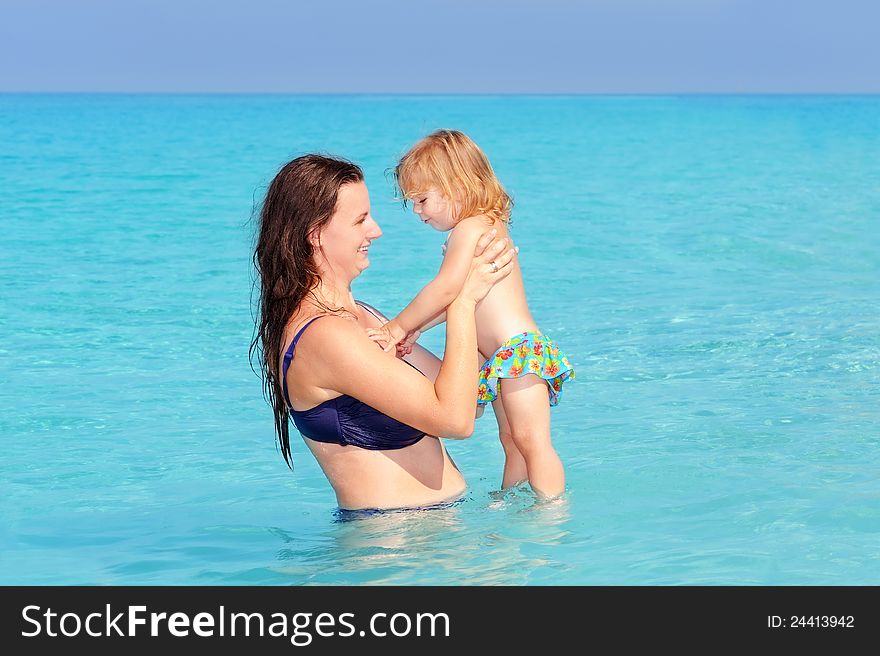 Happy mother with her daughter on the beach, summer vacation concept