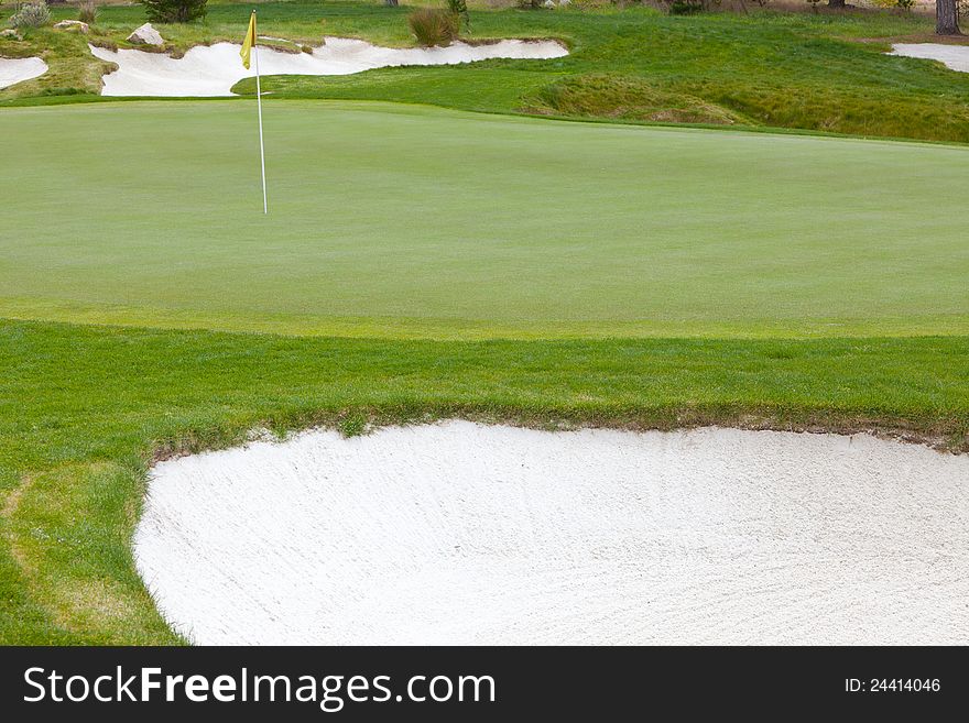 Beautiful, smooth golf green and flag pin surrounded by organically shaped, deep white sand traps. Beautiful, smooth golf green and flag pin surrounded by organically shaped, deep white sand traps