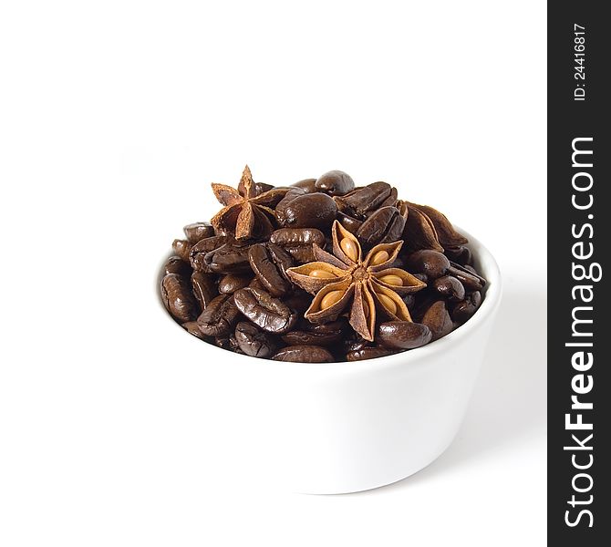 Fresh coffee beans and star anise spice in a white ramekin dish against white background. Copy space. Fresh coffee beans and star anise spice in a white ramekin dish against white background. Copy space.