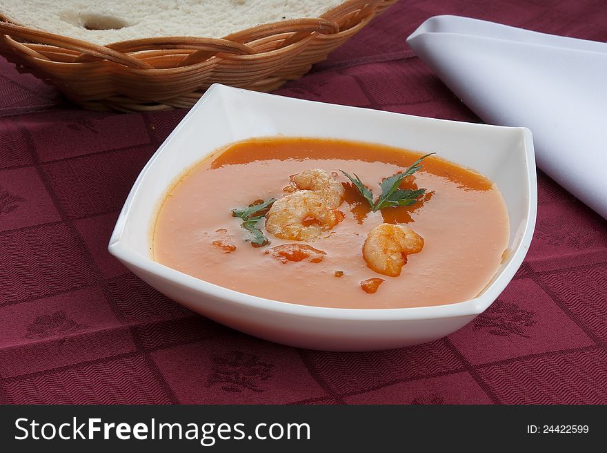 Tomato soup with shrimps and parsley in the white bowl