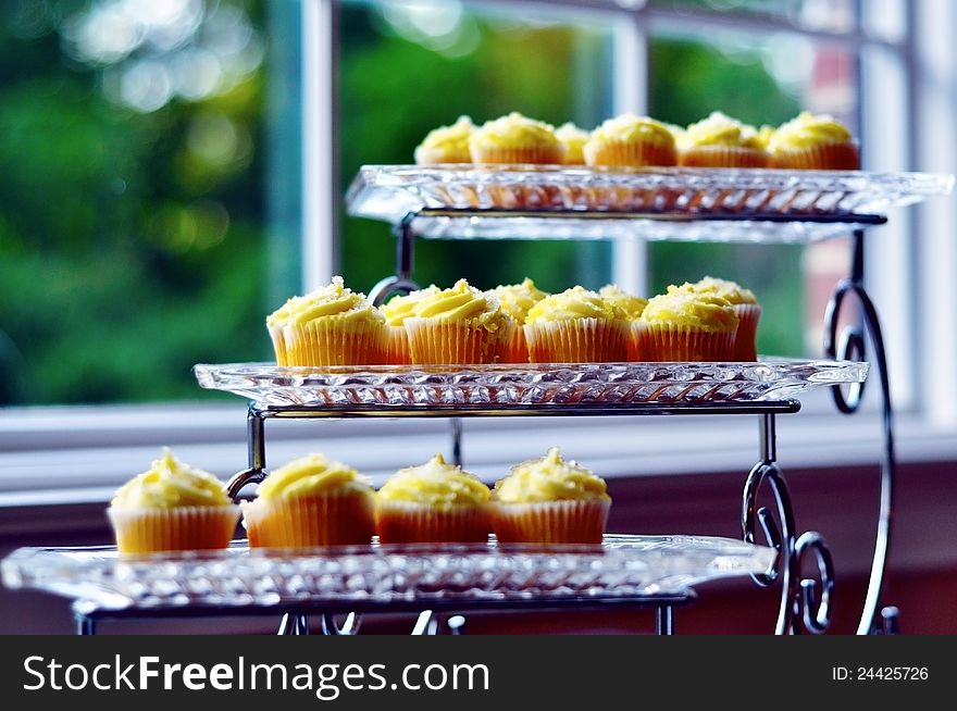 A beautiful stack of canary yellow cupcakes on a 3-tier glass serving platter. A beautiful stack of canary yellow cupcakes on a 3-tier glass serving platter.